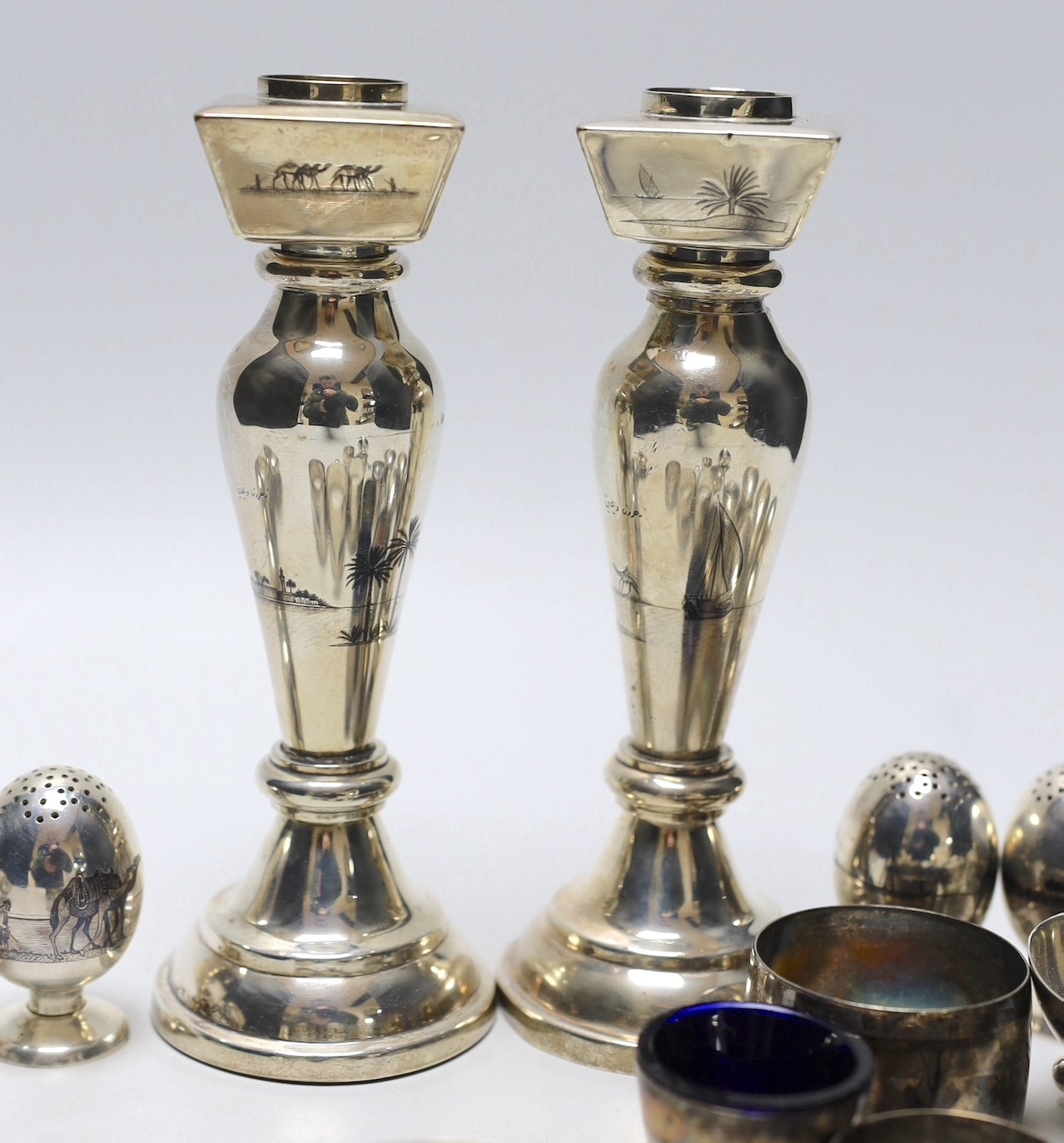 Thirteen assorted Iraq white metal and niello condiments, circular box, five similar napkin rings, a brooch and a pair of similar (damaged) candlesticks.